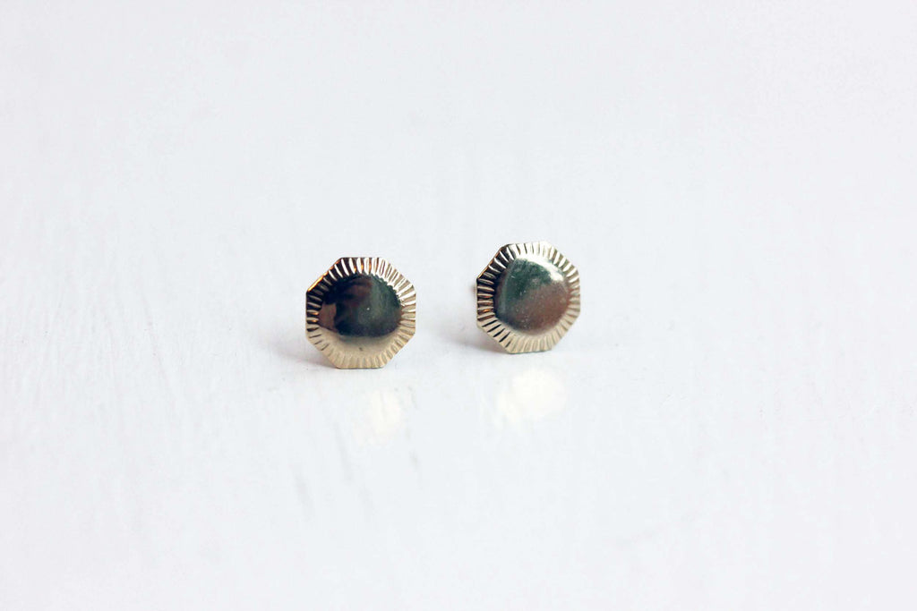 Gold shield studs from Diament Jewelry, a gift shop in Washington, DC.