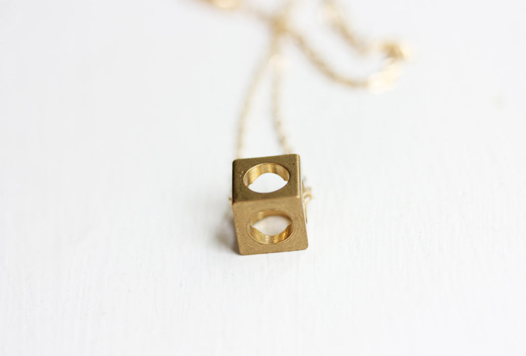 Tiny Brass Cube Necklace from Diament Jewelry, a gift shop in Washington, DC.