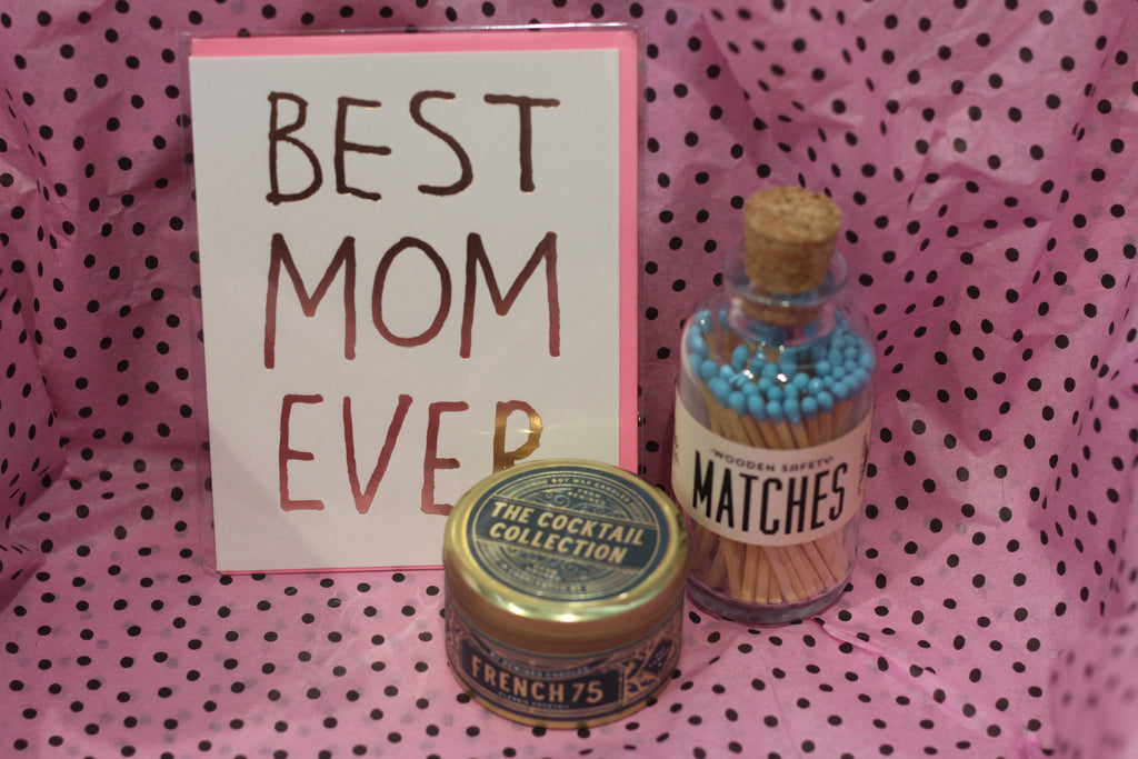 A Mother's Day care package containing a card, wooden safety matches, and a The Cocktail Collection French 75 candle from Diament Jewelry, a gift shop in Washington, DC.