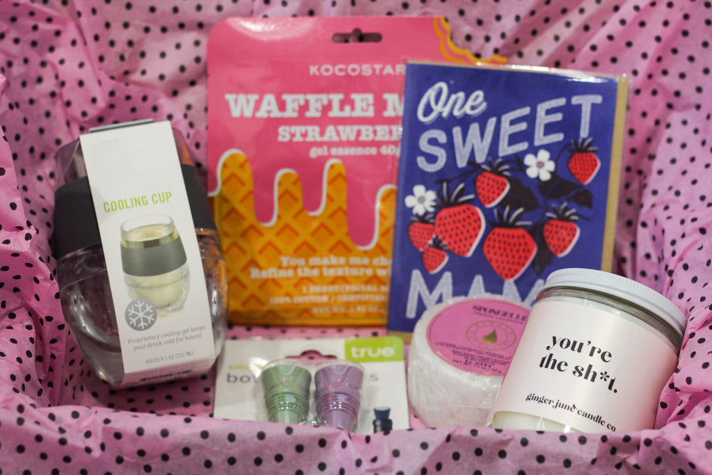 A Mother's Day care package containing a card, face mask, wine cooling cup, plastic wine stoppers, a Spongelle, and funny candle from Diament Jewelry, a gift shop in Washington, DC.