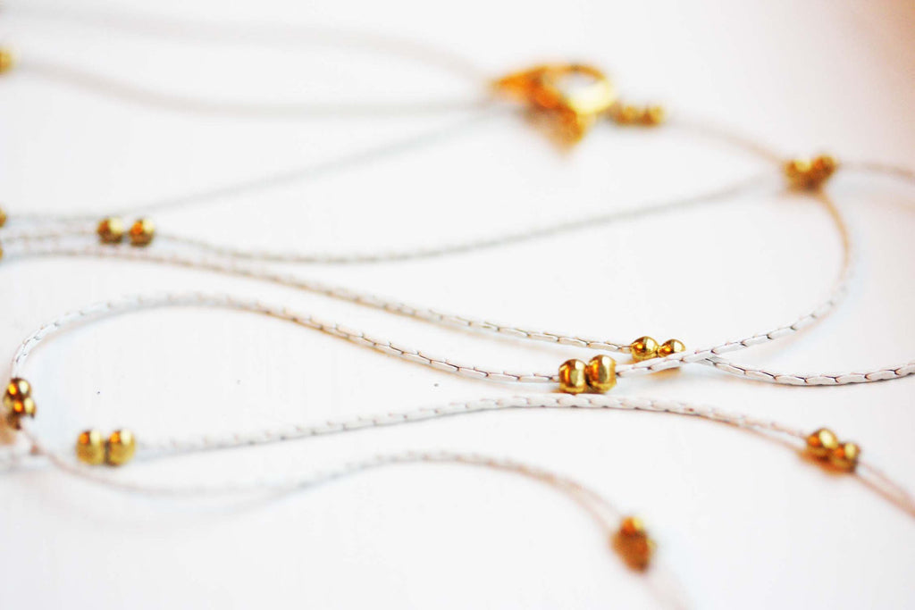 Delicate white and gold long chain necklace from Diament Jewelry, a gift shop in Washington, DC.