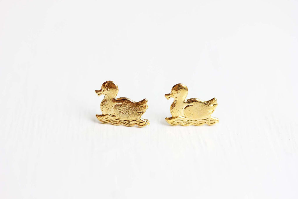 Gold swimming duck studs from Diament Jewelry, a gift shop in Washington, DC.